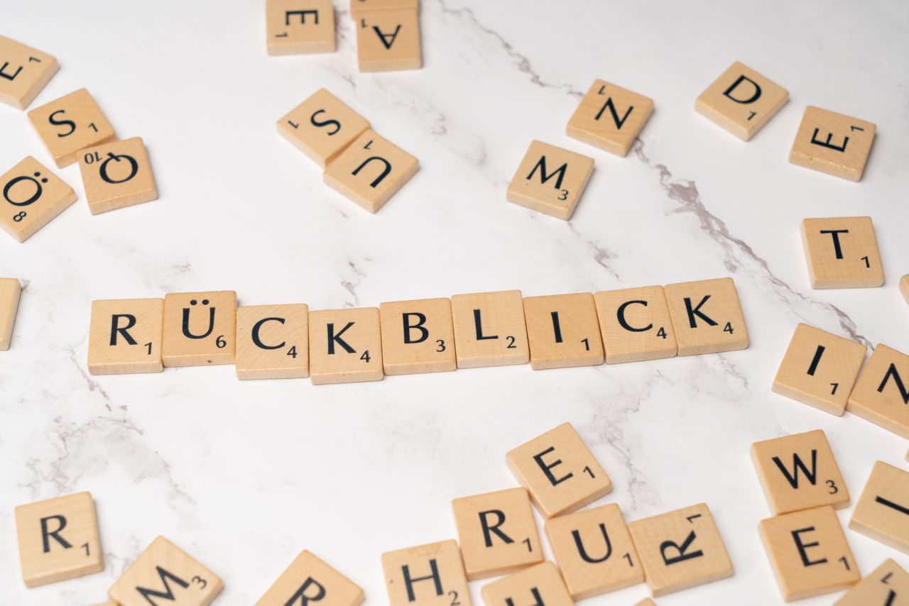 High-angle shot of wooden letter tiles spelling 'Rückblick' on a marble background.